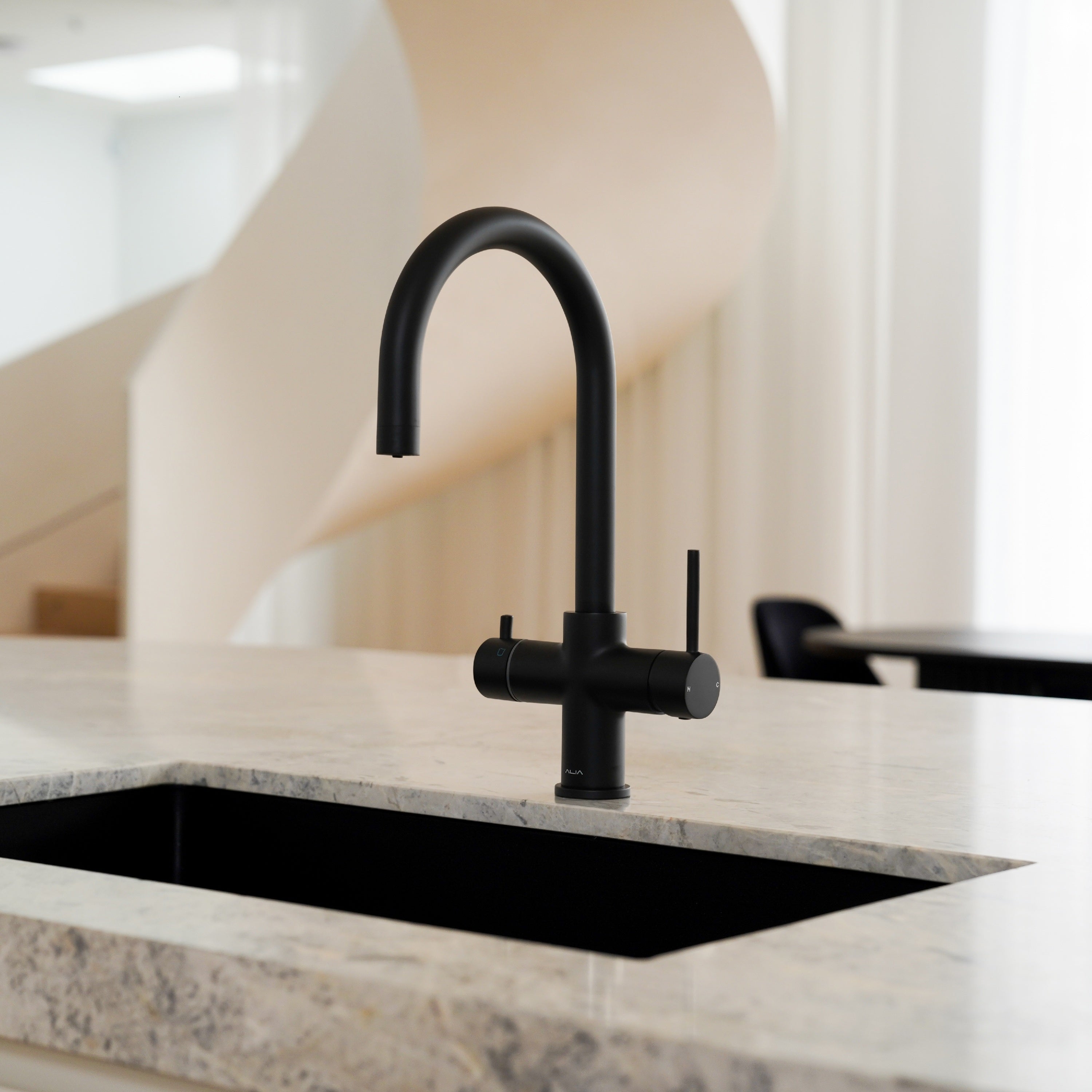 Matte black Alia Global 4-in-1 instant hot filtered water tap featured in a designer kitchen, offering filtered and boiling water with sleek, contemporary style.